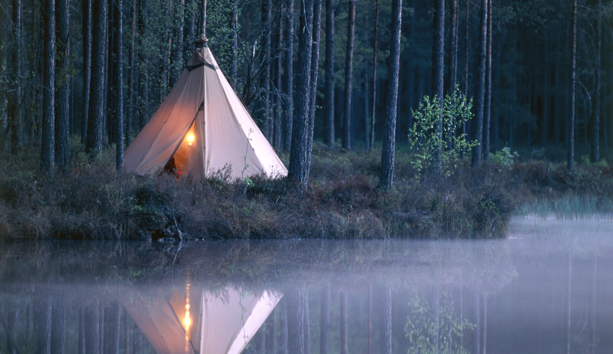 Ett tält som är uppslaget vid ett vacker vatten